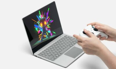 someone holding an xbox controller in front of the microsoft surface laptop go 2