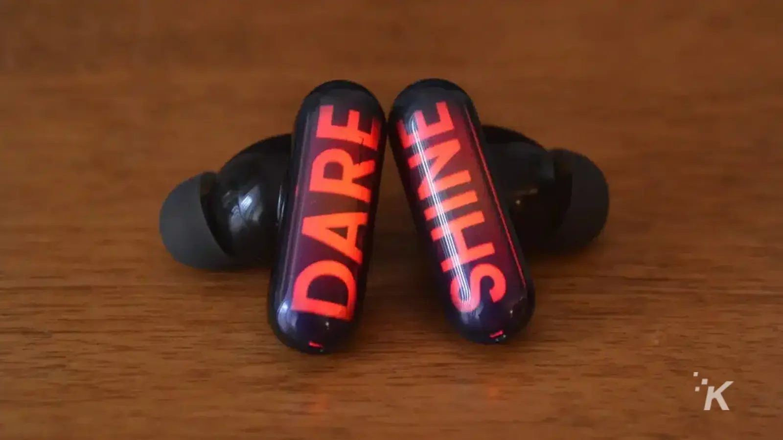 GPods earbuds with the word dare shine led on wooden table