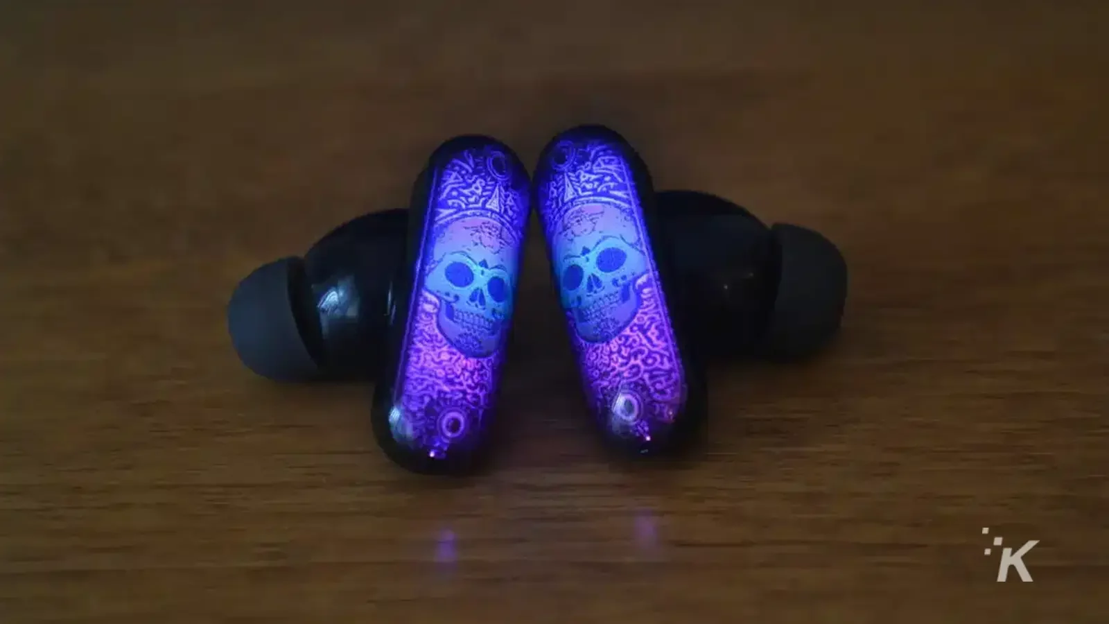 GPods earbuds on wooden table with a purple skeleton design