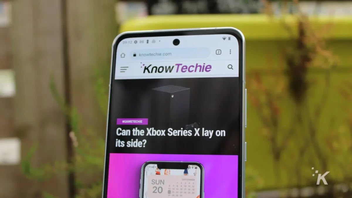 a phone with the KnowTechie website displaying with blurry background