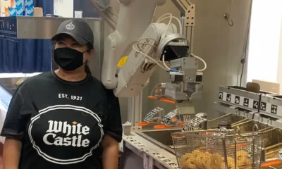 woman standing in front of a burger flipping robot white castle