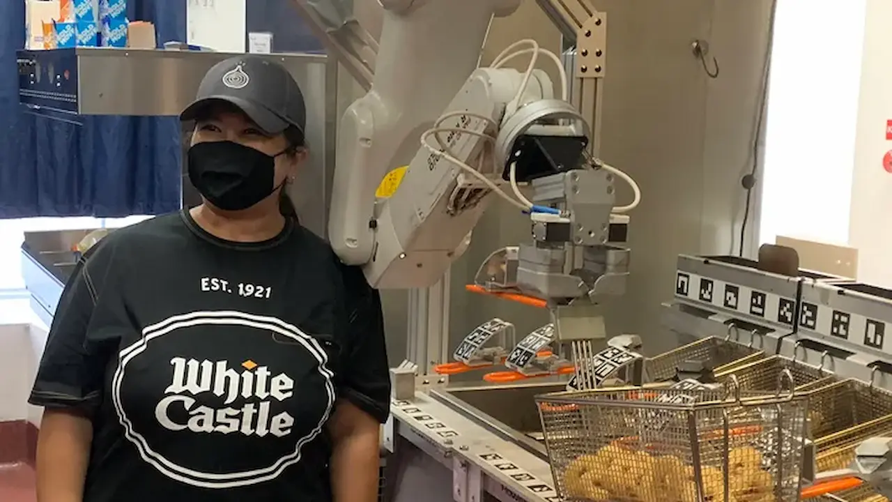 woman standing in front of a burger flipping robot white castle